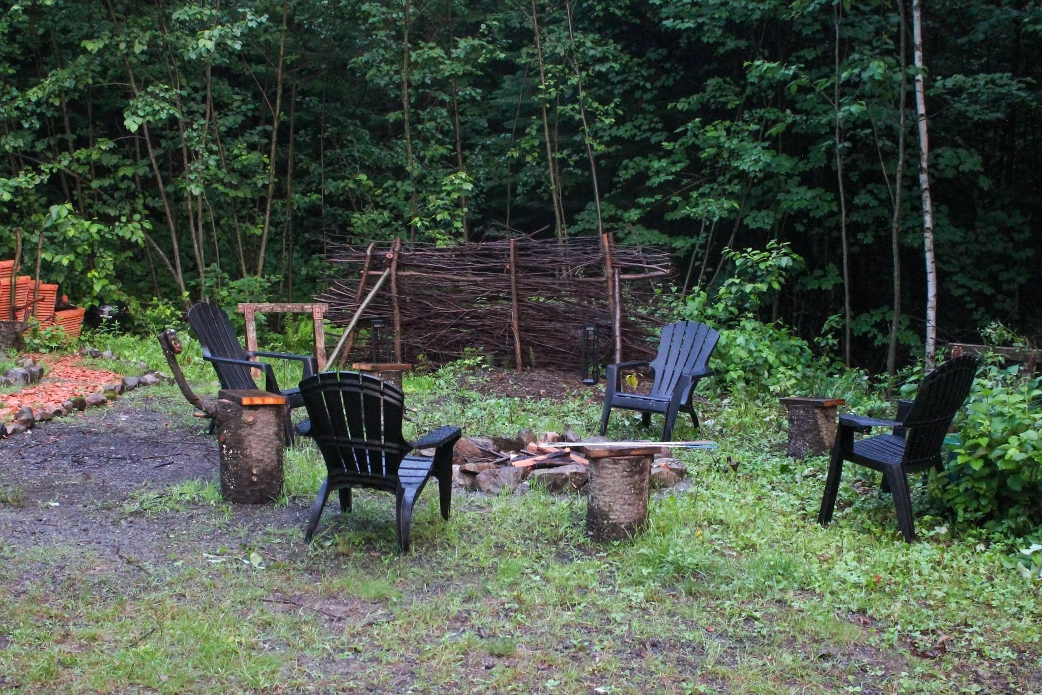 Fire pit surrounded by Adirondack chairs in the forest clearing