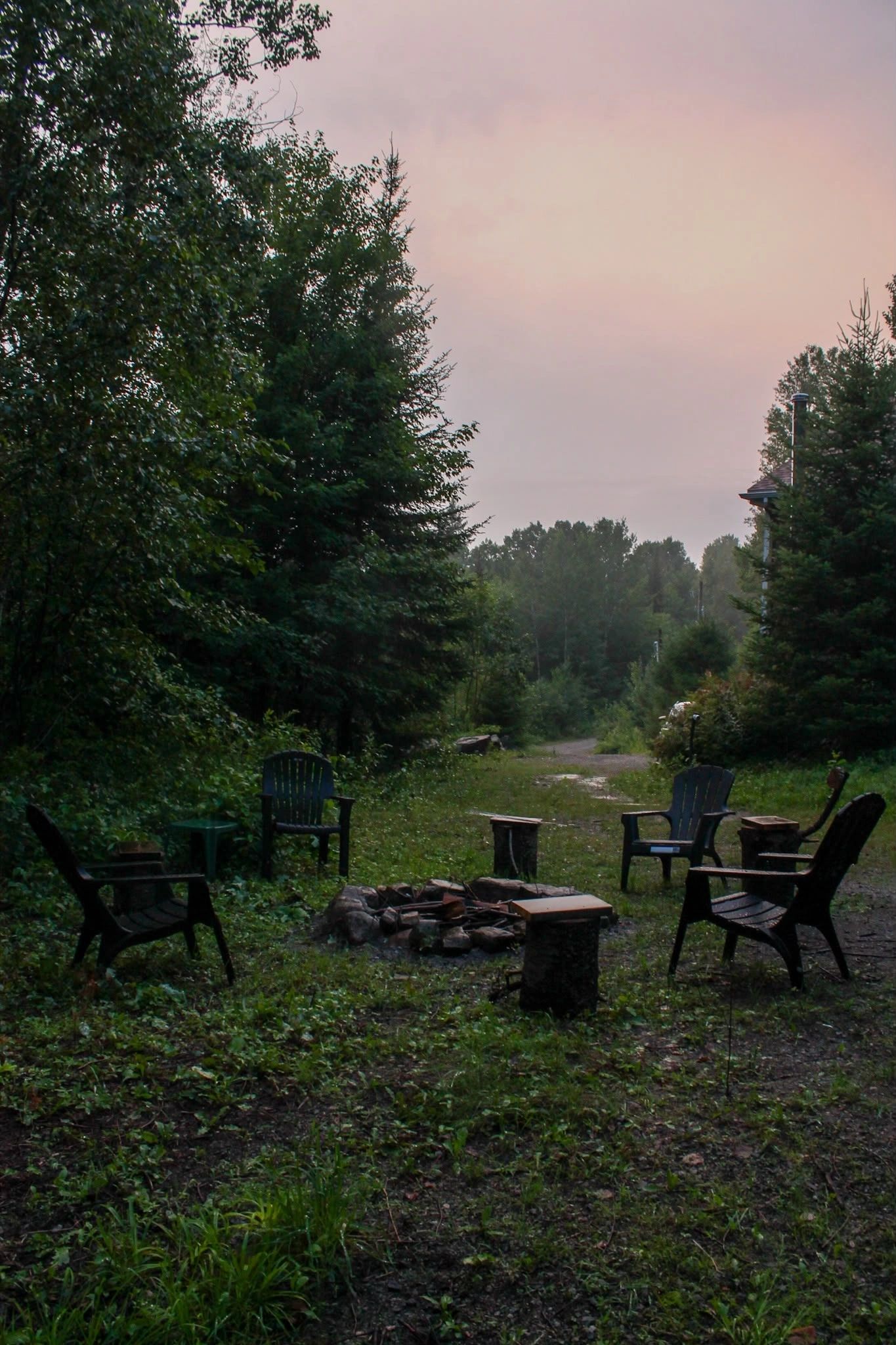 Fire pit at dusk with Adirondack chairs and moody Laurentian sky